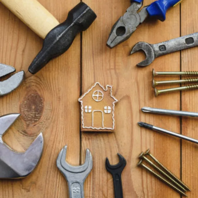 Hand tools and a wooden house cutout, representing Hailey's Co home cleaning, restoration, and maintenance services in San Antonio